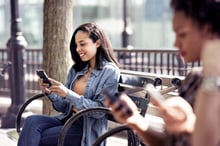 Une femme assise sur un banc sur son téléphone